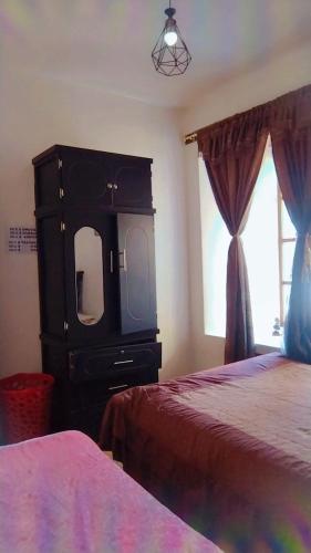 a bedroom with a dresser with a tv and a bed at DEPARTAMENTO SIETE in Quito