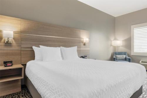 a bed in a hotel room with a large white bed at Best Western Plus Lake Elsinore Inn & Suites in Lake Elsinore