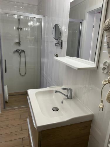 a white bathroom with a sink and a shower at Willa Pan Tadeusz in Łeba