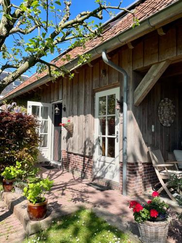 a house with a porch with flowers in front of it at B&B De Pastorie bij Dokkum in Reitsum