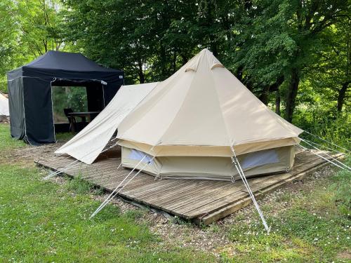 a tent sitting on a wooden platform in a field at Camping Le Canoë in Chaussin