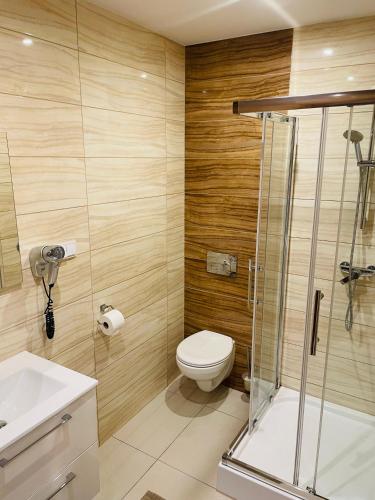 a bathroom with a toilet and a glass shower at Wystrugane Apartamenty in Białka Tatrzanska