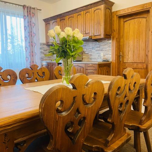 a kitchen with a wooden table with a vase of flowers at Wystrugane Apartamenty in Białka Tatrzanska