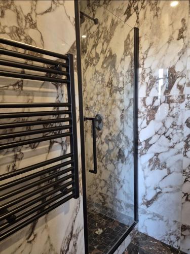 La salle de bains est pourvue d'une douche et d'un mur en marbre. dans l'établissement LUXE-POLE Appartement à 100m de Monaco, à Cap d'Ail