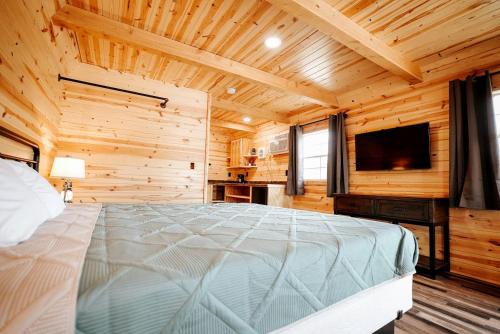 ein Schlafzimmer mit einem Bett und einem Flachbildfernseher in der Unterkunft Stunning Wooden Cabin Nestled Amidst Trees in Rapid City, South Dakota in Rockerville