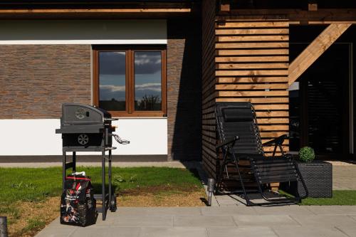 a grill and a chair in front of a house at Pool Villa Mukařov in Srbín