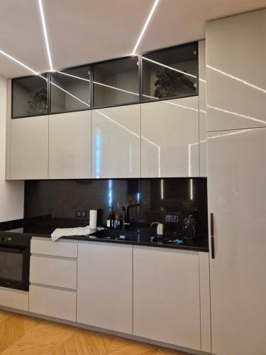 une cuisine avec des armoires blanches et des comptoirs noirs dans l'établissement LUXE-POLE Appartement à 100m de Monaco, à Cap d'Ail