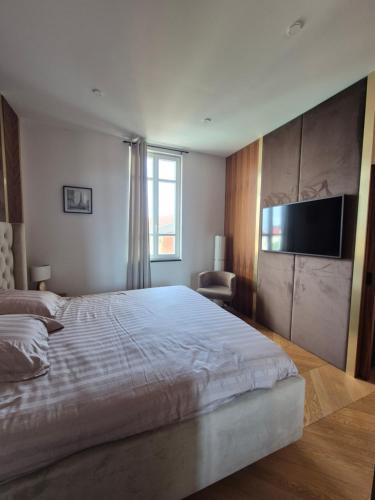 une chambre avec un grand lit et une télévision à écran plat dans l'établissement LUXE-POLE Appartement à 100m de Monaco, à Cap d'Ail