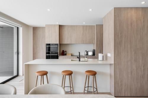 a kitchen with a island with bar stools at Green Coast Beachfront Retreat By Minhos Guest in Apúlia