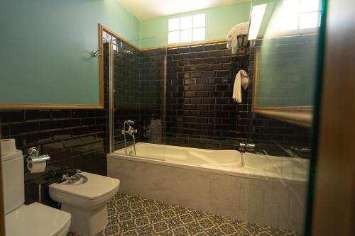 a bathroom with a toilet and a tub and a sink at Hotel Finca las Beatas in Villahermosa