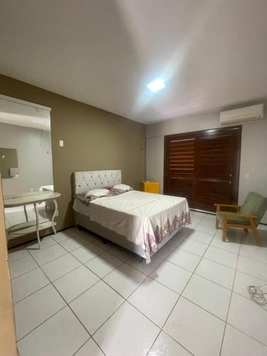 a bedroom with a bed and a table and a chair at Duplex à 800 mts do Beach Park COM 5 suítes in Aquiraz