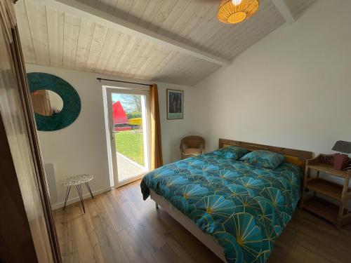 une chambre avec un lit avec une couette bleue et une fenêtre dans l'établissement Gite de charme trois chambres au pied des marais grand jardin, à LʼÎle-dʼOlonne