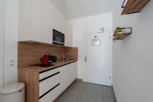 a small kitchen with white cabinets and a sink at Vienna Stay Apartments Schönbrunn in Vienna