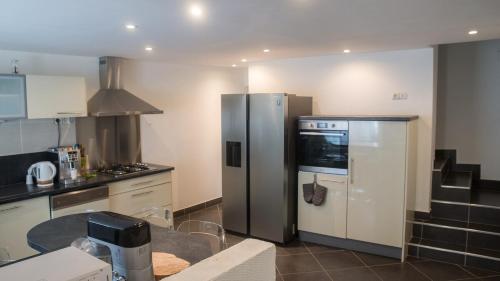 une cuisine avec un réfrigérateur en acier inoxydable et une table dans l'établissement Maison de ville meublée 60m2, à Saint Etienne