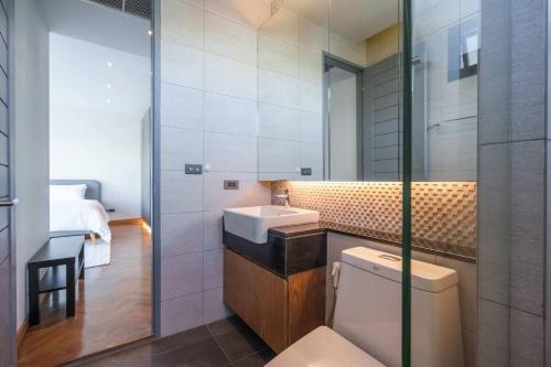 Un baño con inodoro, lavabo y cama. en MonochromeDesignerPool Villa, en Ban Na Song