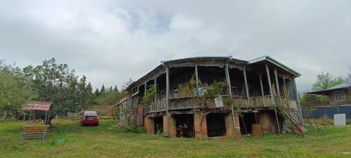 an old building in a field with a car at Gia's Home in Vazisubani in Vazisubani