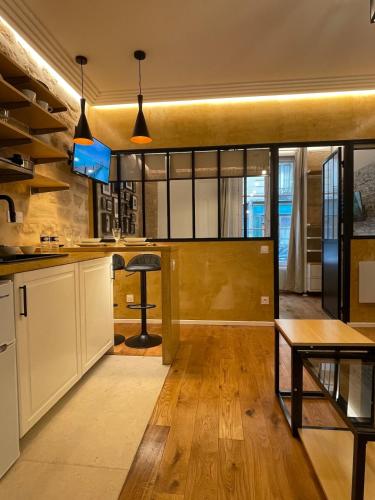 une cuisine avec des armoires blanches et une table dans une pièce dans l'établissement Cozy Loft Montmartre Place des Abbesses Sacré Cœur, à Paris