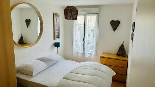 une chambre avec un lit avec un miroir et une fenêtre dans l'établissement Coquillages et crustacés à Cayeux sur mer, à Cayeux-sur-Mer