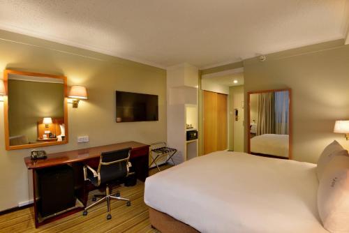a hotel room with a bed and a desk with a computer at Holiday Inn - Harare by IHG in Harare