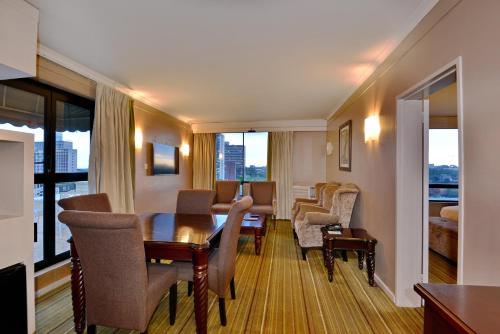 a hotel room with a table and chairs and a living room at Holiday Inn - Harare by IHG in Harare