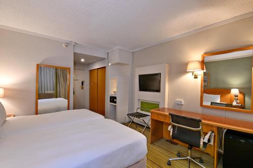 a hotel room with a large bed and a desk at Holiday Inn - Harare by IHG in Harare