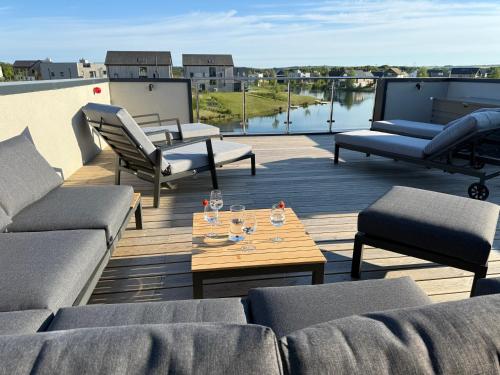 a deck with couches and a table with wine glasses on it at Still Waters - Luxury Lakeside Retreat with Hot Tub in Warmwell