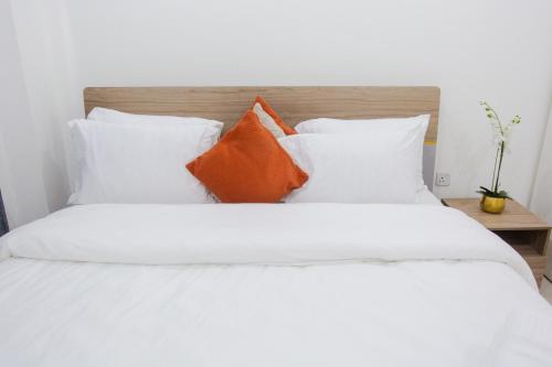 a bed with white sheets and orange pillows at Accra Luxury Apartments at The Gallery in Accra