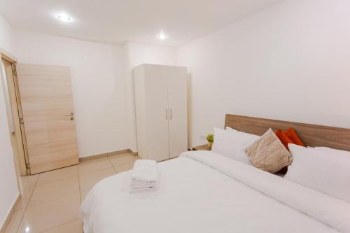 a bedroom with a large bed with white sheets at Accra Luxury Apartments at The Gallery in Accra