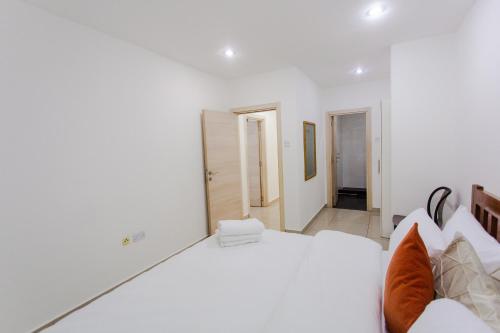a white bedroom with a large white bed with orange pillows at Accra Luxury Apartments at The Gallery in Accra