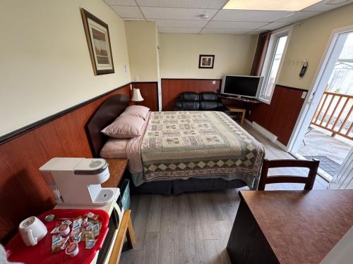 a small hotel room with a bed and a table at Merritt Lodge in Merritt