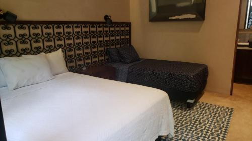 a bedroom with a white bed and a chair at Casa Boutique Pashá in Mérida