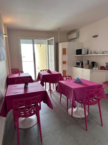 eine Küche mit rosa Tischen und Stühlen in einem Raum in der Unterkunft la bussola gallipoli in Gallipoli