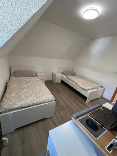 two beds in a room with a laptop on a desk at Frische Luft in Meschede