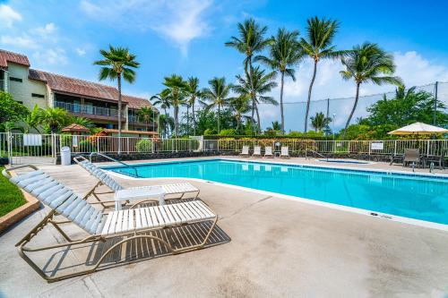 a pair of lounge chairs next to a swimming pool at Big Island Keauhou Punahele A301 by Coldwell Banker Island Vacations in Kailua-Kona