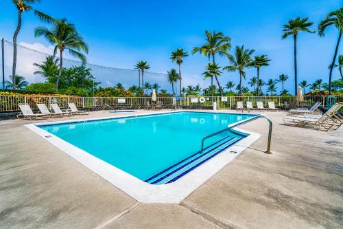 a swimming pool with chairs and palm trees at Big Island Keauhou Punahele A301 by Coldwell Banker Island Vacations in Kailua-Kona