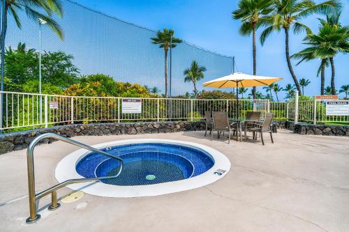 a hot tub in a patio with a table and umbrella at Big Island Keauhou Punahele A301 by Coldwell Banker Island Vacations in Kailua-Kona