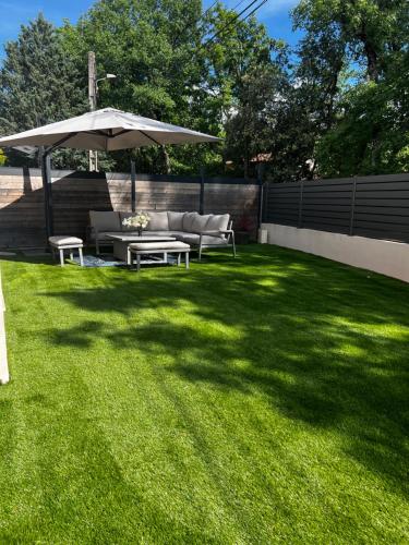 a lawn with a couch and an umbrella at Maison la Cocagne de la Sainte Baume in Nans-les-Pins
