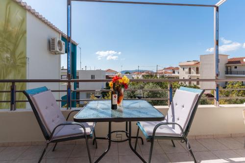 a table with chairs and a vase of flowers on a balcony at Sun George in Finikounta
