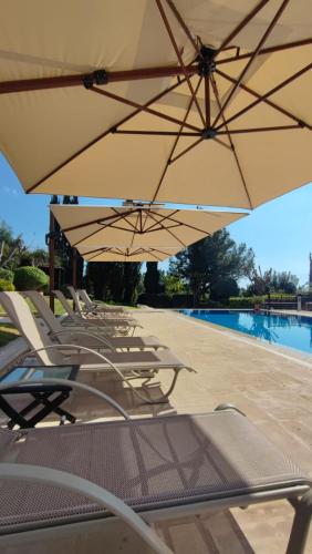 a group of chairs and umbrellas next to a pool at Villa UNIDERA in Kouklia