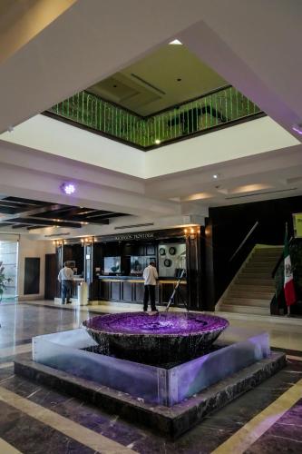 a lobby with a fountain with purple flowers in the middle at Royal Palace in Hermosillo