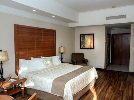 a bedroom with a large bed and a chair at Royal Palace in Hermosillo