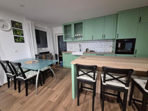 a kitchen with green cabinets and a table and chairs at TaWorld apartment in Šmartno pri Litiji