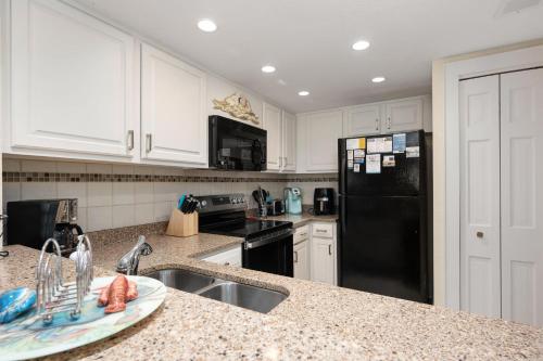 a kitchen with a sink and a black refrigerator at QA4 Coastal Comfort in Nags Head