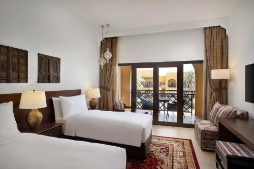 a hotel room with two beds and a balcony at Aldhafra Desert Resort, Vignette Collection by IHG in Madīnat Zāyid