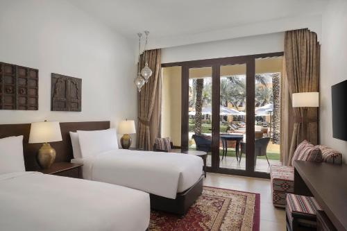 a hotel room with two beds and a patio at Aldhafra Desert Resort, Vignette Collection by IHG in Madīnat Zāyid