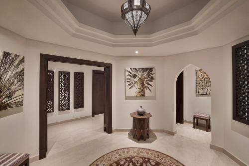a hallway of a home with a table and paintings at Aldhafra Desert Resort, Vignette Collection by IHG in Madīnat Zāyid