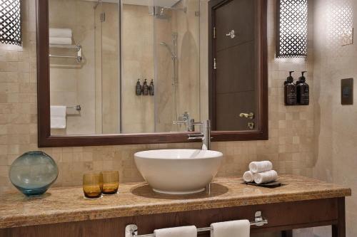 a bathroom with a sink and two glasses on a counter at Aldhafra Desert Resort, Vignette Collection by IHG in Madīnat Zāyid
