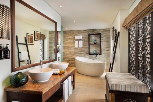 a bathroom with two sinks and a bath tub at Aldhafra Desert Resort, Vignette Collection by IHG in Madīnat Zāyid
