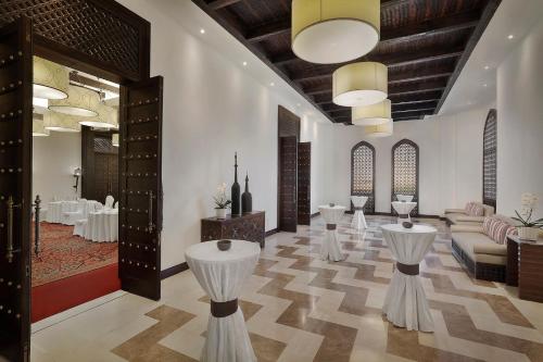 a lobby with tables and chairs in a room at Aldhafra Desert Resort, Vignette Collection by IHG in Madīnat Zāyid