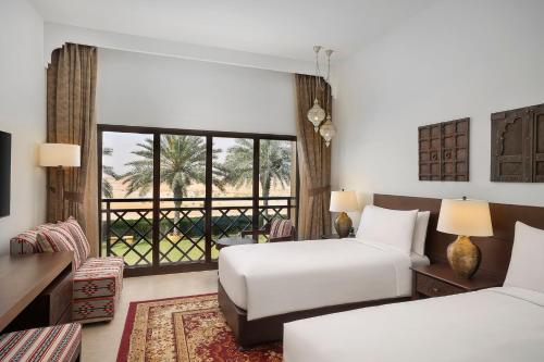 a hotel room with two beds and a balcony at Aldhafra Desert Resort, Vignette Collection by IHG in Madīnat Zāyid